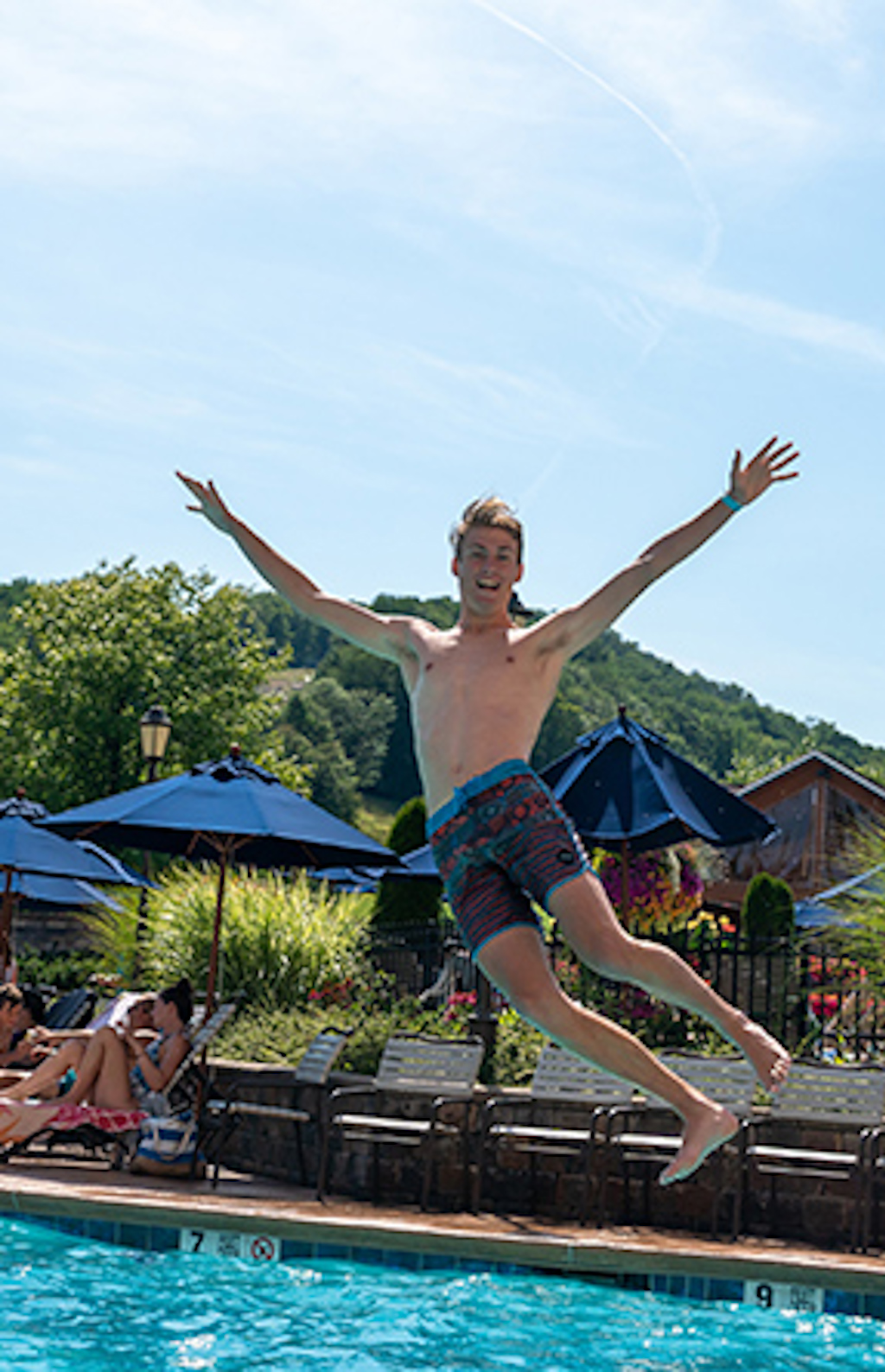 A young man looking at the camera as he jumps into a pool at Holiday Valley.